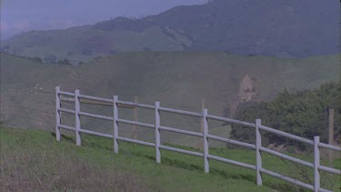 green countryside rolling hills with post and rail fence in foreground