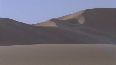 wind blowing sand down sand dune shadow in background