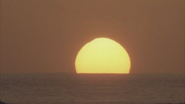 Sun setting behind ocean.