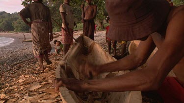 Carving a native Sampan canoe on shore