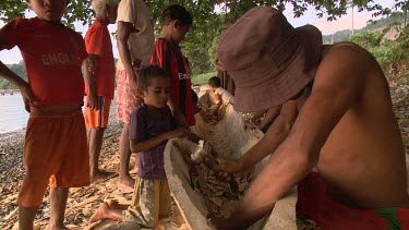 Carving a native Sampan canoe on shore