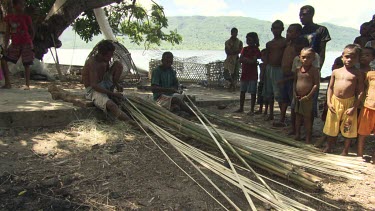 Villagers splitting bamboo on the beach