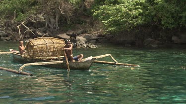 Locals paddling a canoe with a large fish trap by the coast