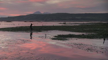 Villager on a low tide reef at sunset