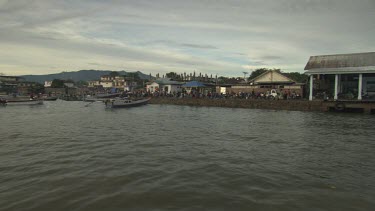 Tender boat arriving to a busy harbour and fish market