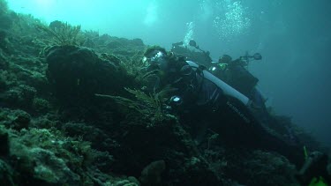 Pair of scuba divers clinging to a reef