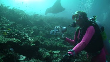 Manta Ray swimming behind a scuba diver with a camera