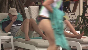 Couple in bathing suits relaxing on lounge chairs