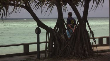 Man staring contemplatively at the ocean from a pier