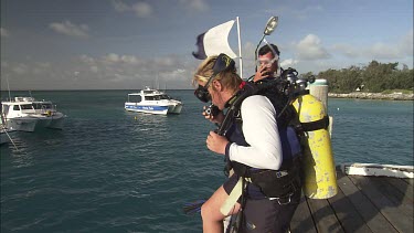 Pair of scuba divers jumping into the water