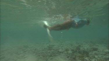 Two girls snorkeling and inspect the coral reef.