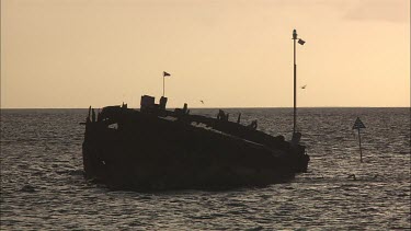 Kids are swimming next to the ruins of the ship.