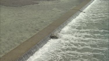 Water streaming along the beach shore. Known as tidal water. Ship wrecked in baclground.