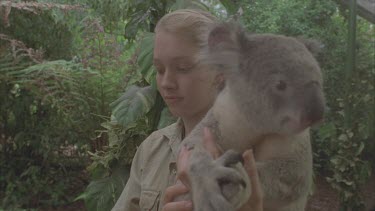 Handler passing koala bear to child to hold