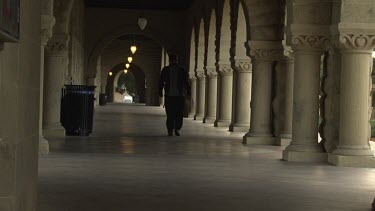 Man walking down a corridor with columns