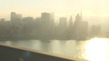 Driving on a bridge into a hazy city at sunrise