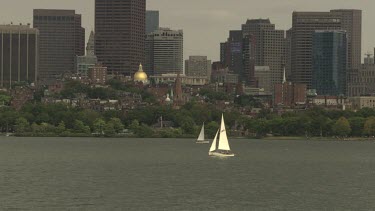 Sailboats in the water outside a city on a cloudy day