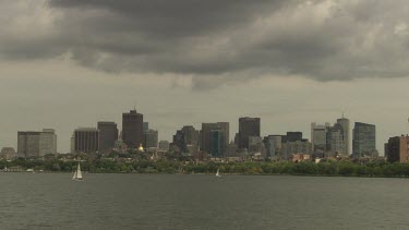 Sailboats in the water outside a city on a cloudy day