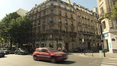 Traffic and pedestrians going by an old hotel