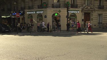 Traffic and pedestrians going by an old hotel