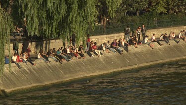 People sitting on the bank of the Seine river, Paris, France
