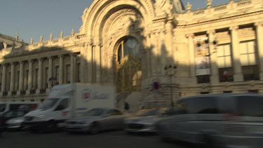 Driving by a building with tall columns and archways