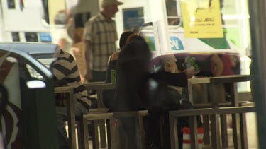 People sitting at tables in a glass building with pedestrians reflected outside