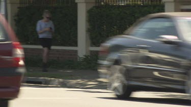 Woman walks down the street texting on her smartphone