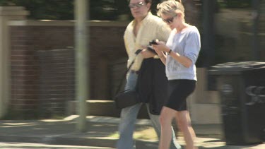 Woman walks down the street texting on her smartphone