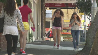 Friends talking and texting on their smartphones on a street corner