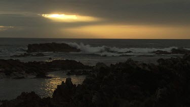 Waves breaking against a rocky shore at sunset