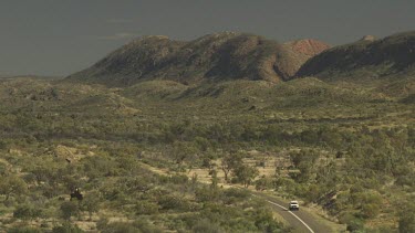 Driving a winding road through dry vegetation in a mountain valley