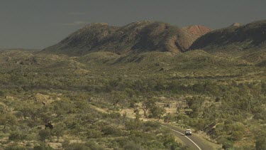 Driving a winding road through dry vegetation in a mountain valley