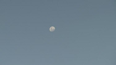 Faint moon in a clear blue sky