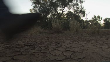 Hiker walking across a dry, cracked riverbed