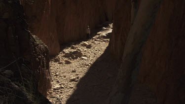 Hikers walking a narrow path between two high cliffs