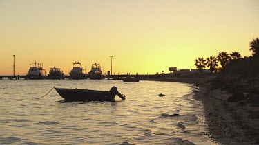 Silhouette of a boat moored off the coast at sunset