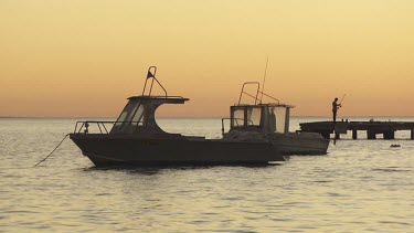 Boats moored in a harbour at sunset