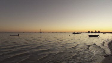 Boats moored in a harbour at sunset