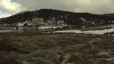 Fountain spraying water by a building in snowy mountains