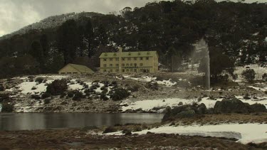 Fountain spraying water by a building in snowy mountains