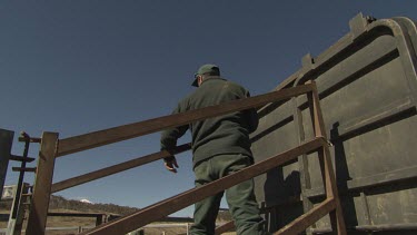 Farmer hitches a horse trailer to a paddock