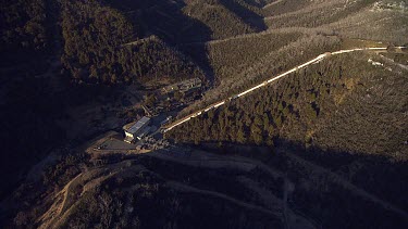 Road to a building through a forested mountain range