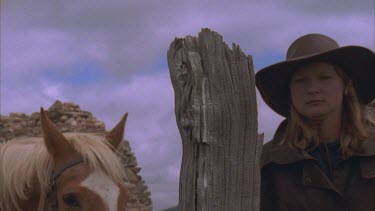 horse riders dismount and tie reins around fence post stone homestead remains in background