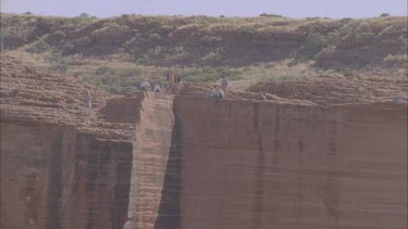 pull back from tourist resting in Canyon to reveal extent of the rock face and gorge