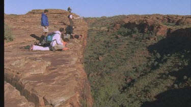 tourist standing on edge of Canyon to reveal height and steepness of rock face pan to sandstone domes on other side of gorge