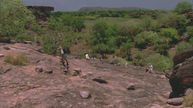 people walking up towards Ubirr rock art site tilt to reveal entire rock