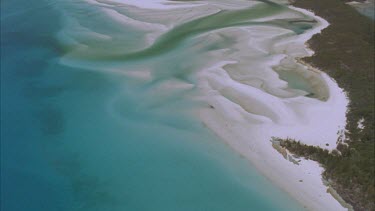 tracking shots over the great barrier reef from deep blue water to continental island and then over Whitehaven inlet white sands and estuary complex winding its way through island. Sandy bottomed rive...