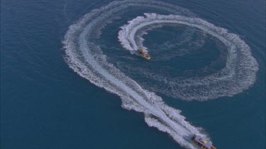 track over blue waters and 2 powerboats under motor with matching bow waves make a P shape