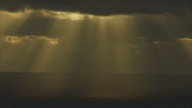 Sunset with shaft of light coming through clouds and lighting the ocean